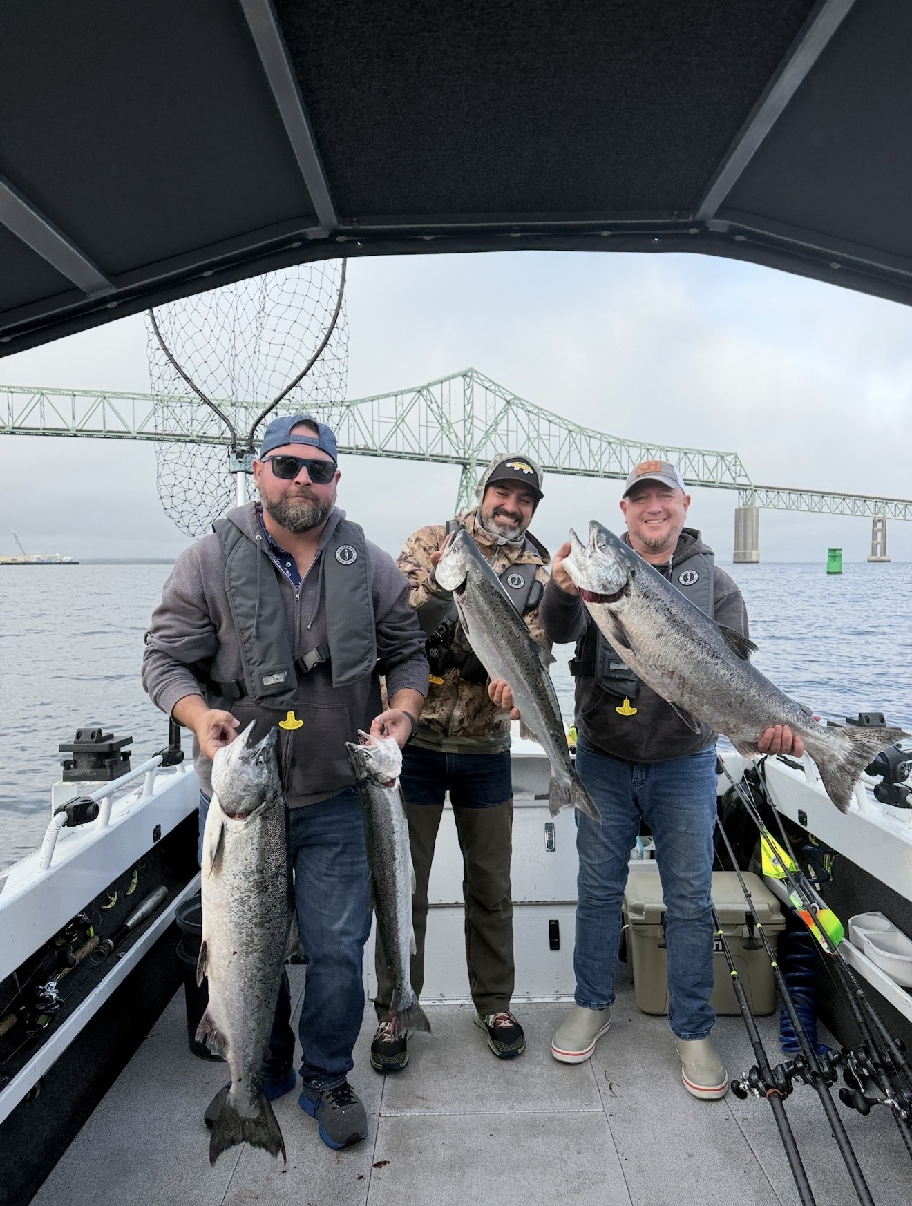 Three anglers on the boat with Chinook salmon under the Astoria–Megler Bridge