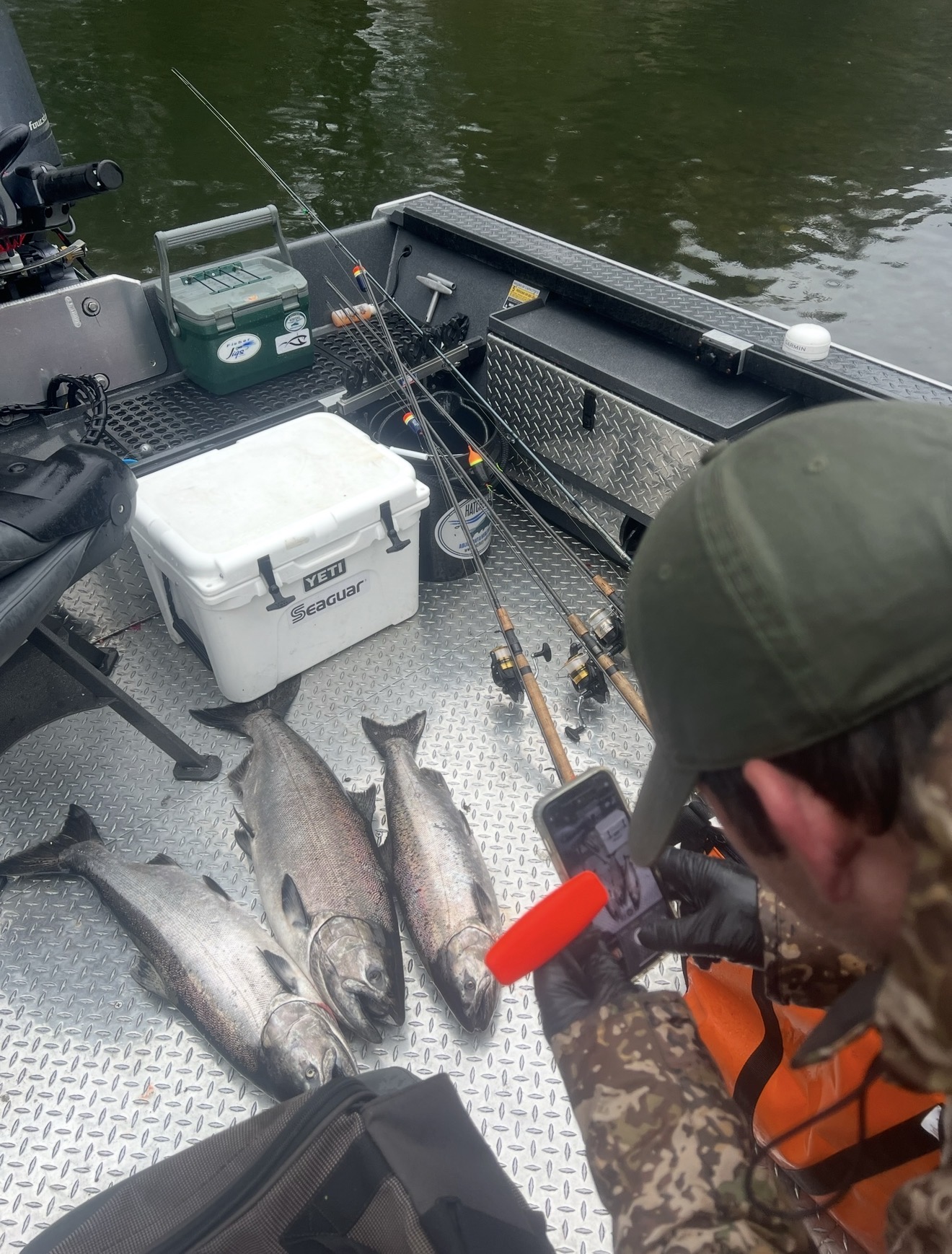 Three fresh Chinook salmon on the boat deck with rods and Yeti cooler