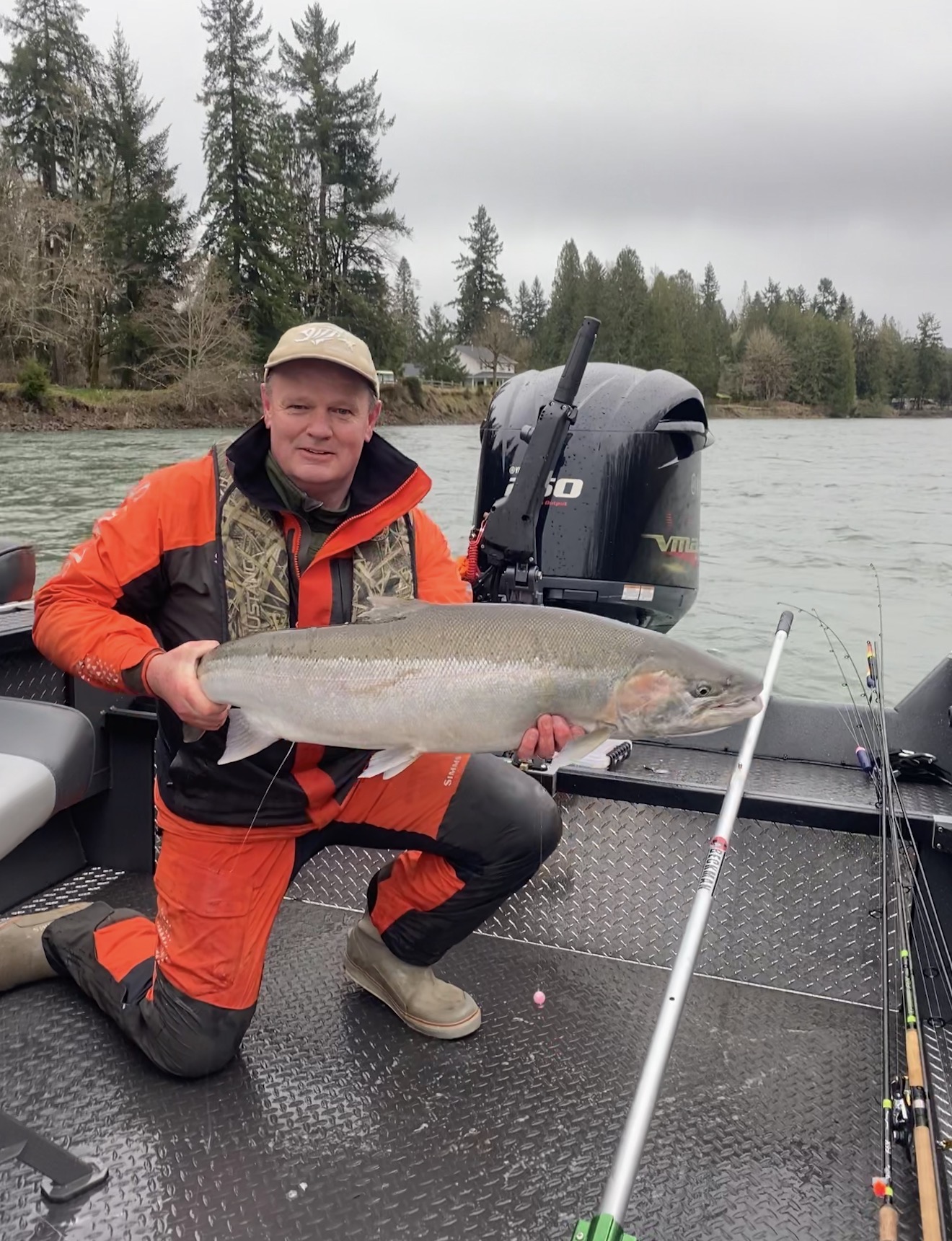 Client kneeling on the boat with a bright chrome winter steelhead