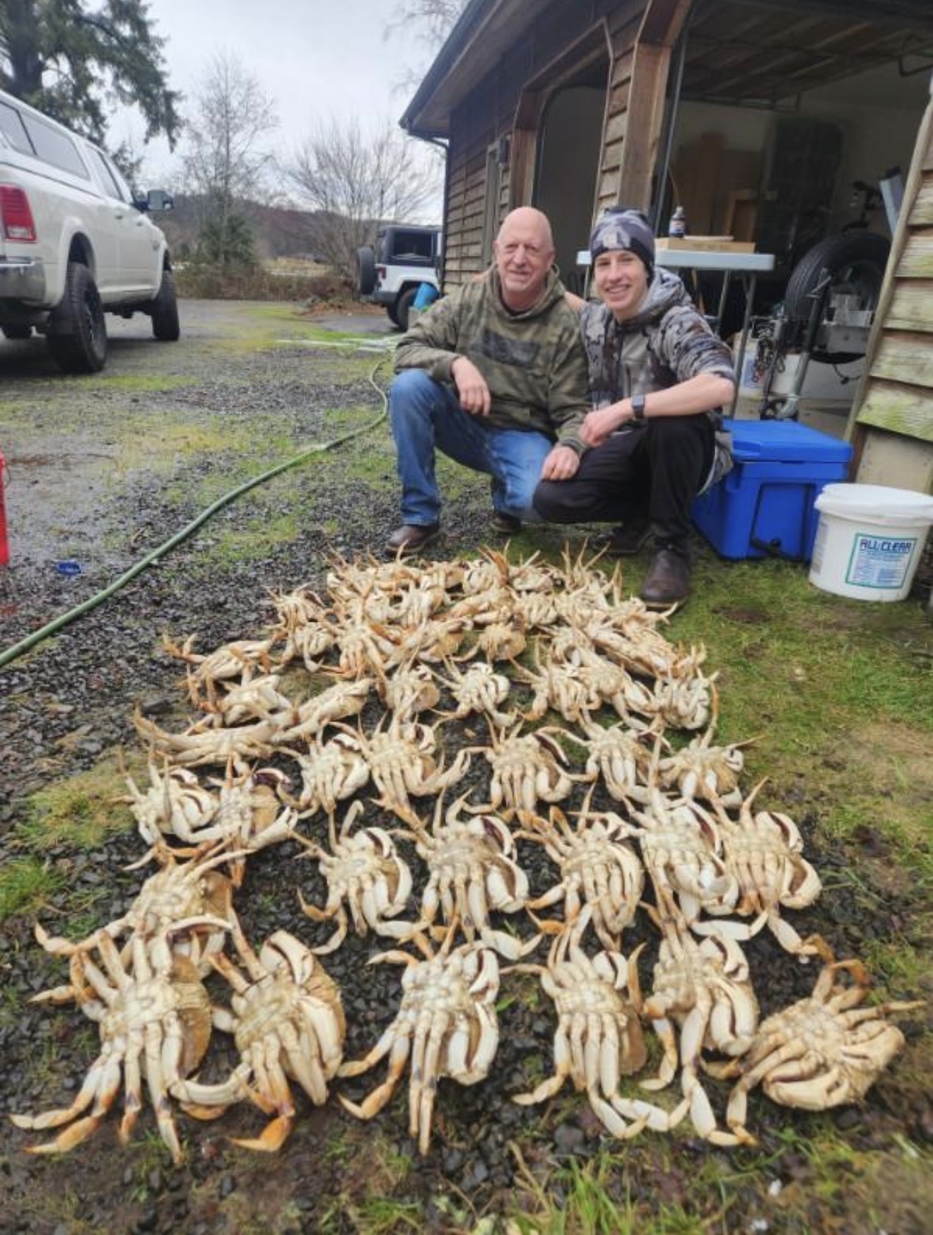 Deckhand kneeling behind a pile of Dungeness crab on the boat