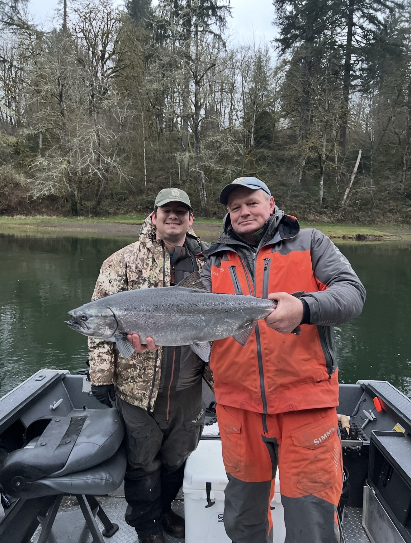 Two anglers on the boat with a bright river Chinook