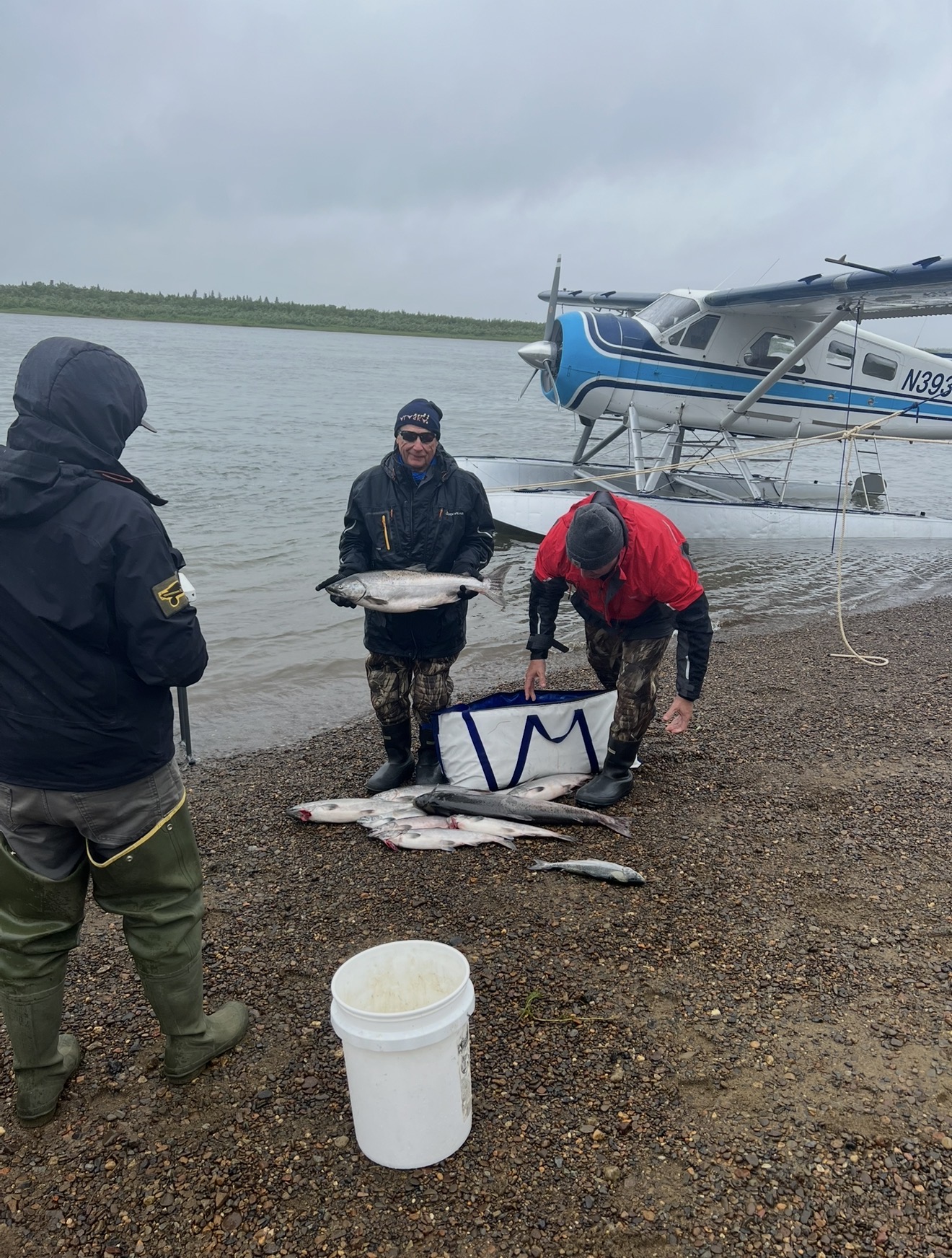 Clients on the beach with a pile of salmon beside a float plane