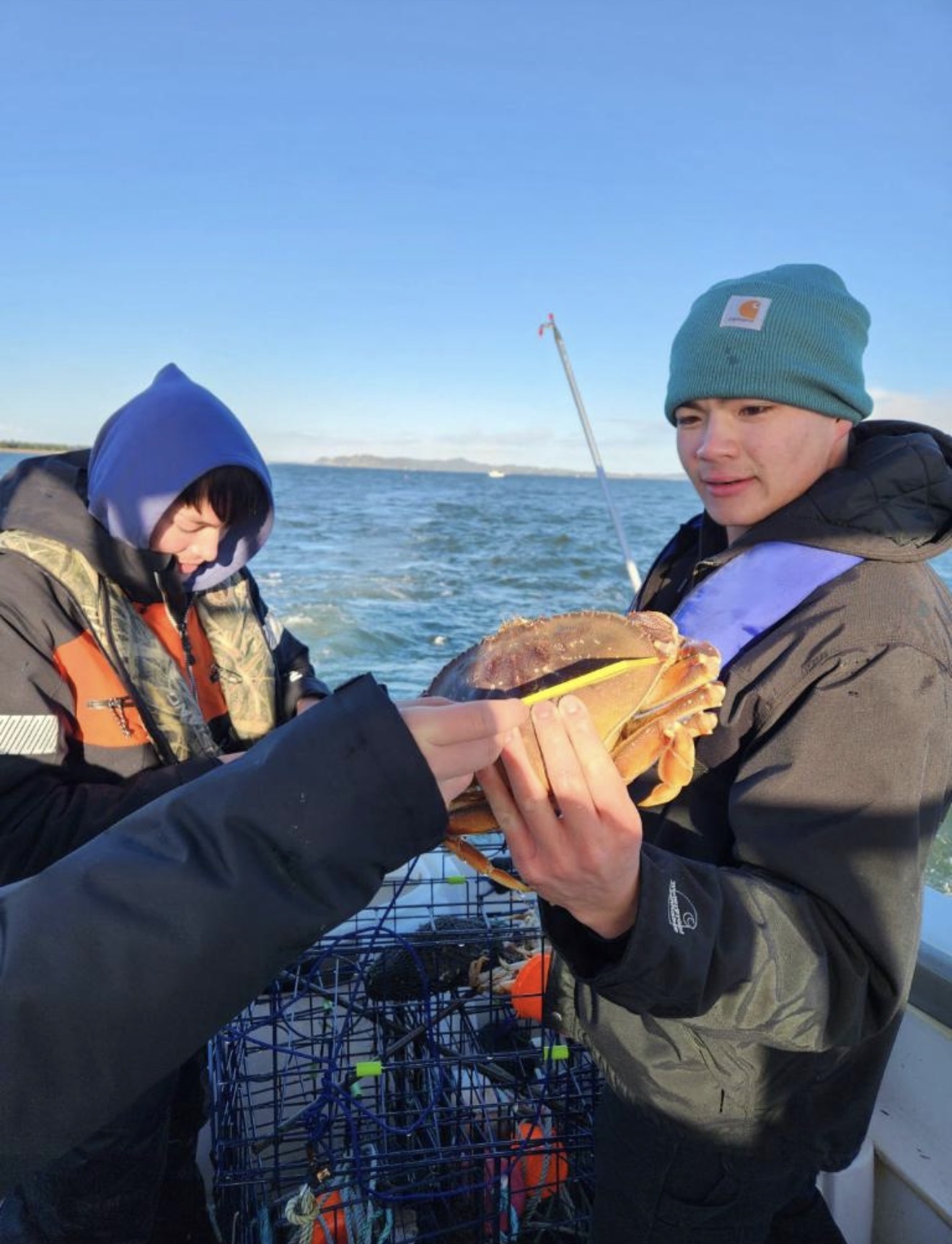 Two young anglers holding a big Dungeness crab on the boat near Astoria