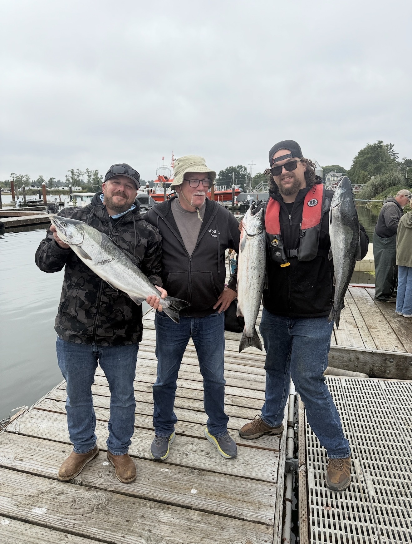 Three happy clients on the dock holding bright Chinook salmon after a trip