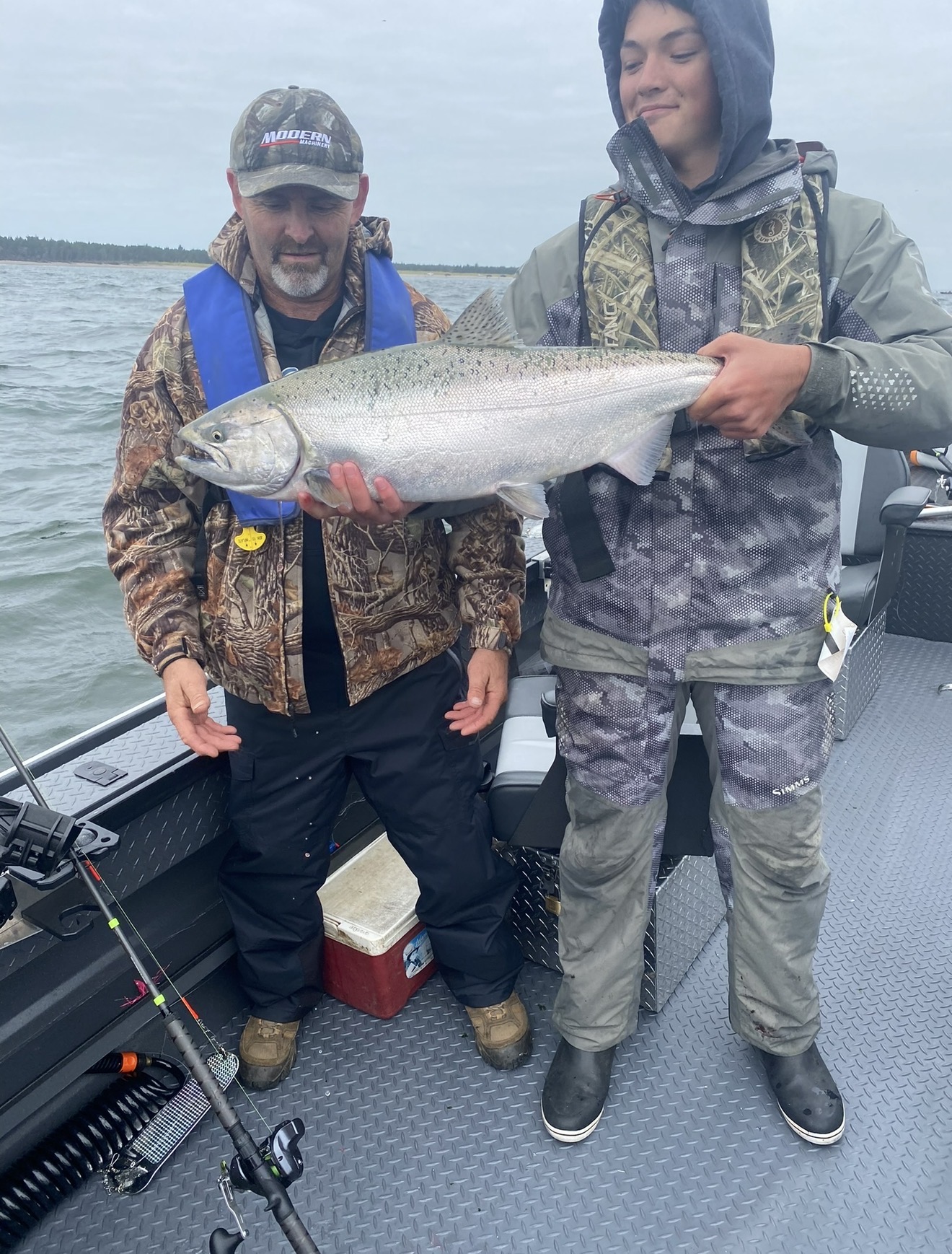Two anglers on the boat holding a massive Buoy 10 Chinook salmon