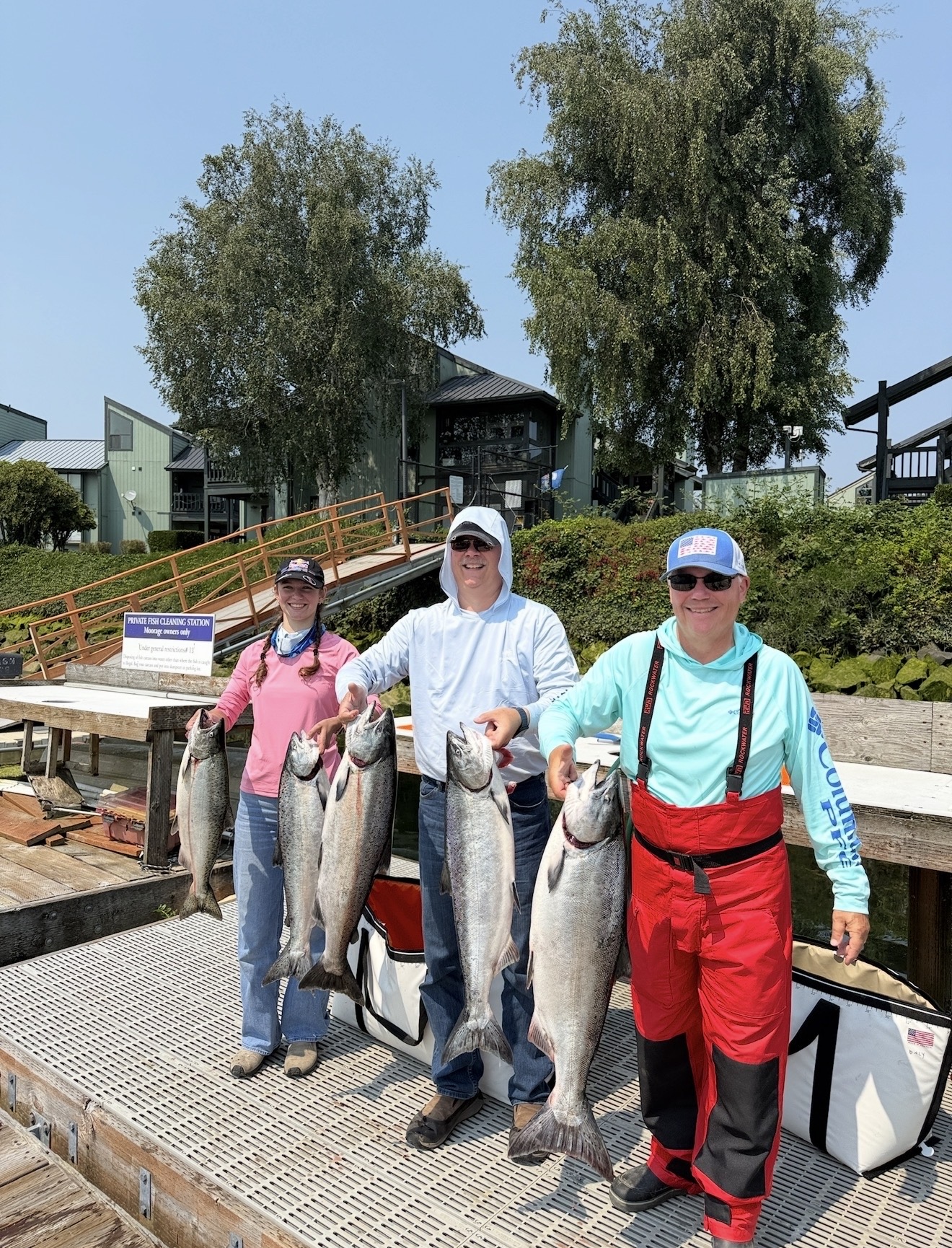 Three anglers on the fish cleaning dock holding a limit of bright Columbia River Chinook salmon