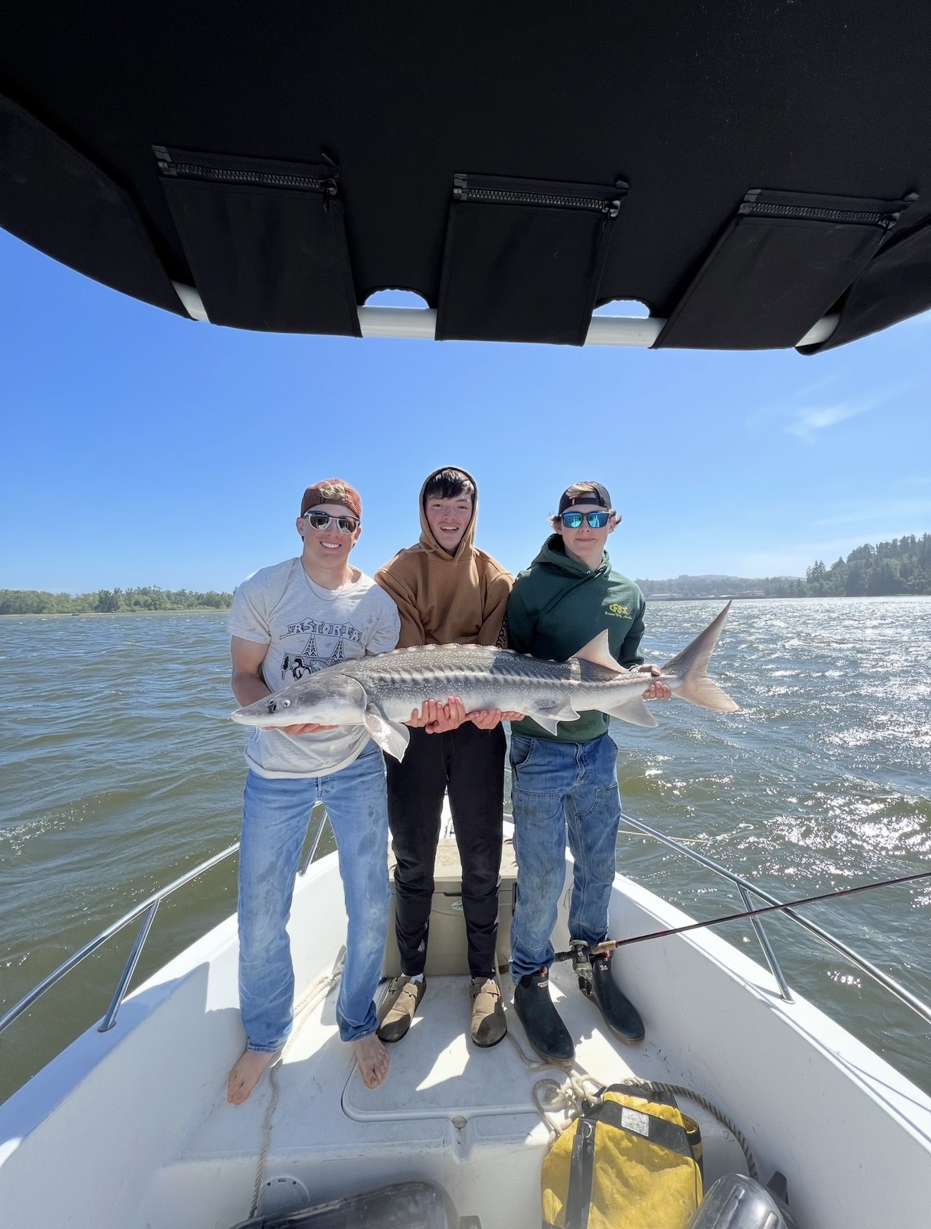 Three anglers holding a keeper sturgeon on the bow of the Willie Nemesis