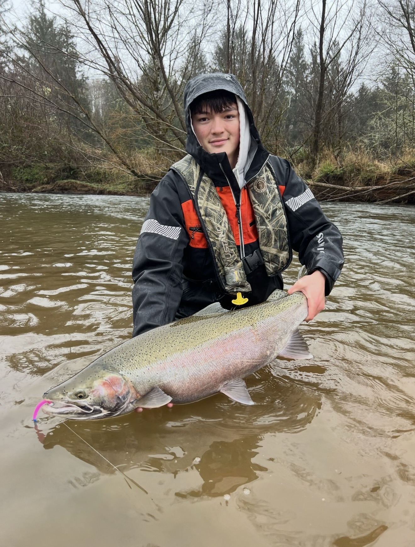 Angler in the river with a huge buck steelhead