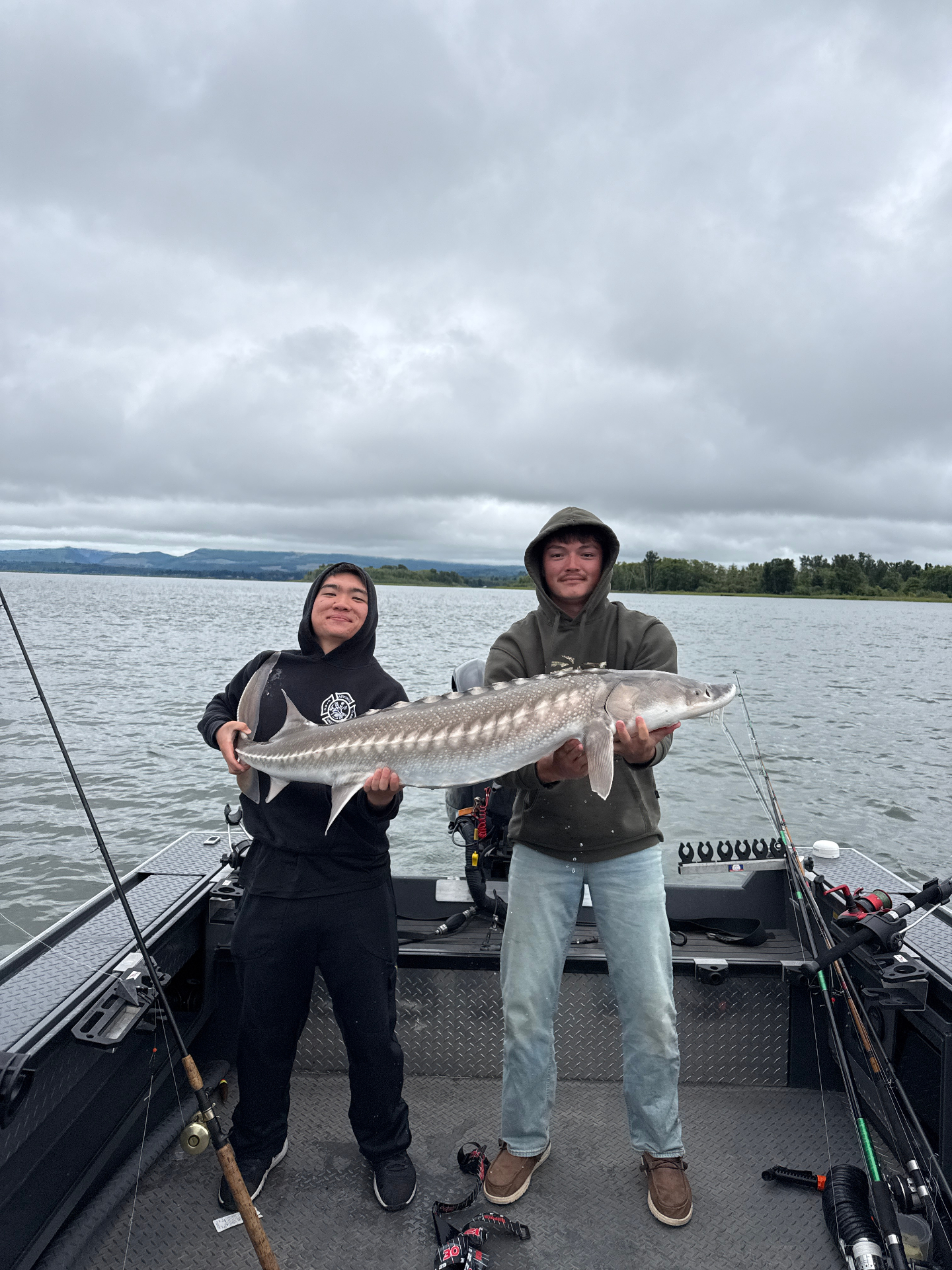 Two anglers on the boat holding a chrome Columbia River sturgeon