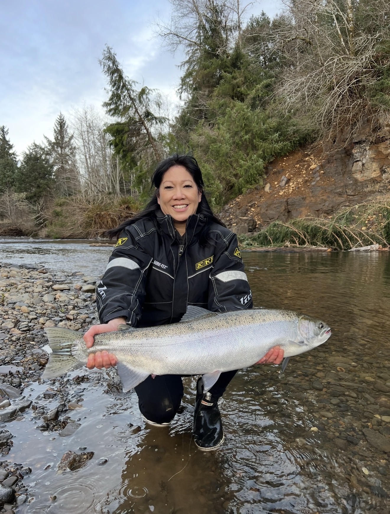 Client kneeling on the bank with a chrome hen steelhead