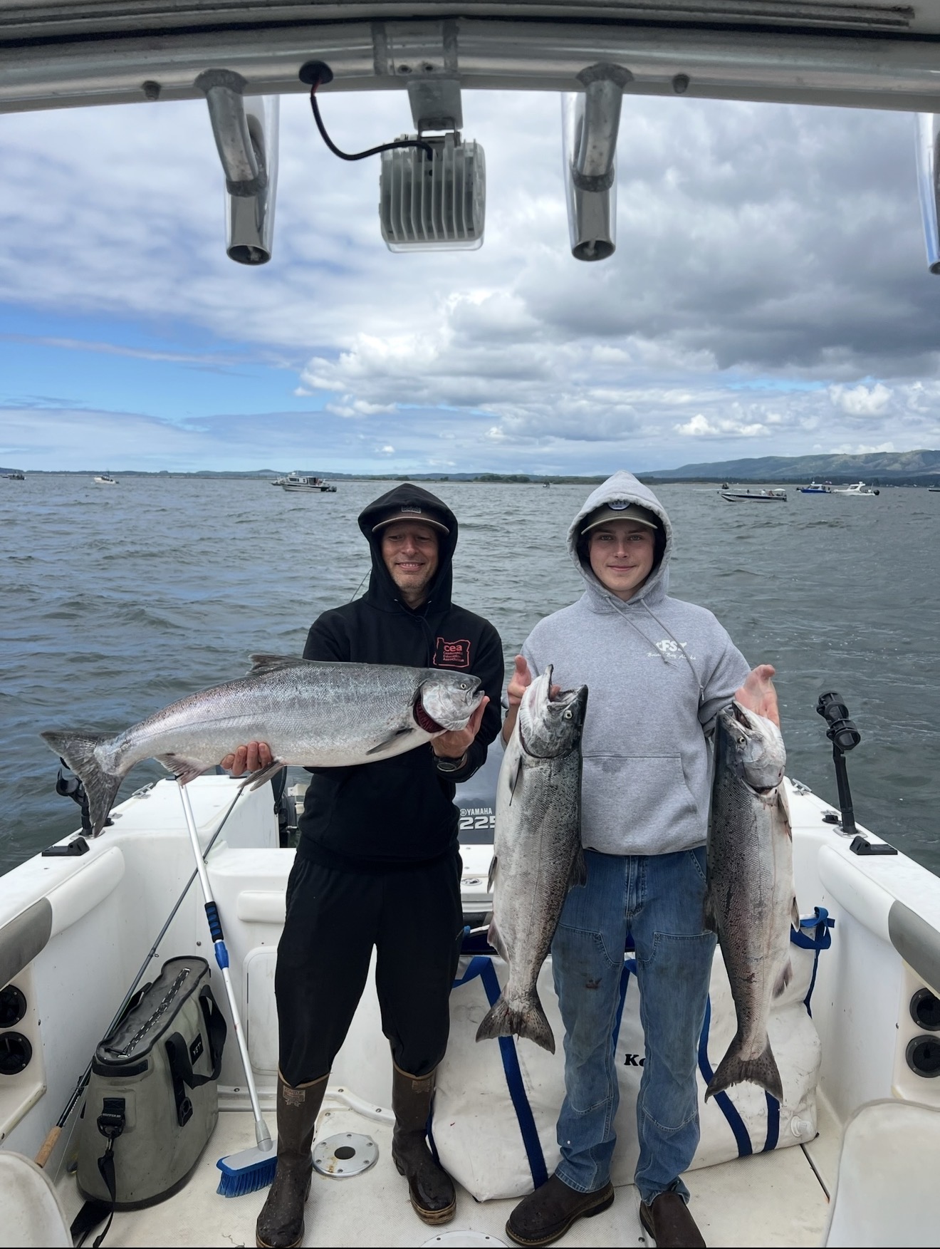 Two clients on the boat holding three bright Chinook salmon offshore