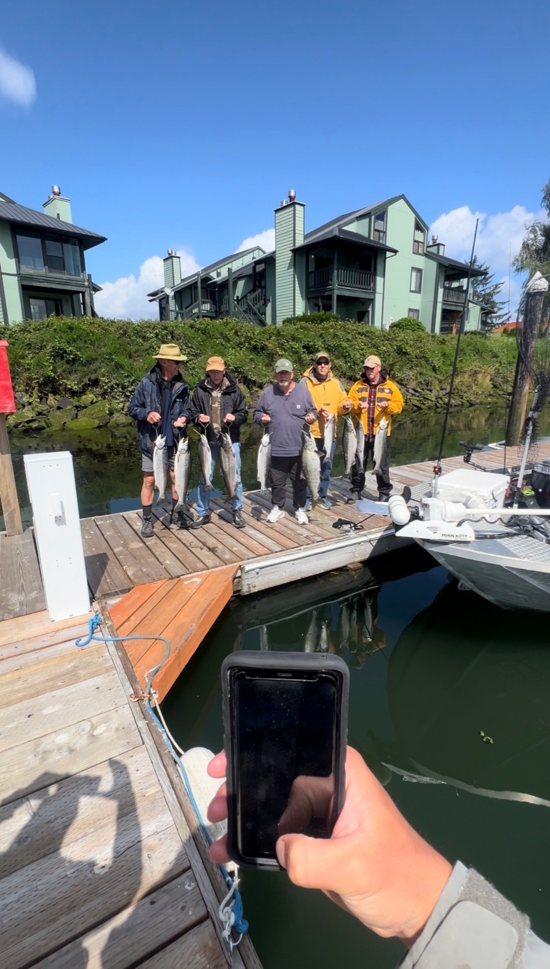 Five clients on the dock holding their salmon catch