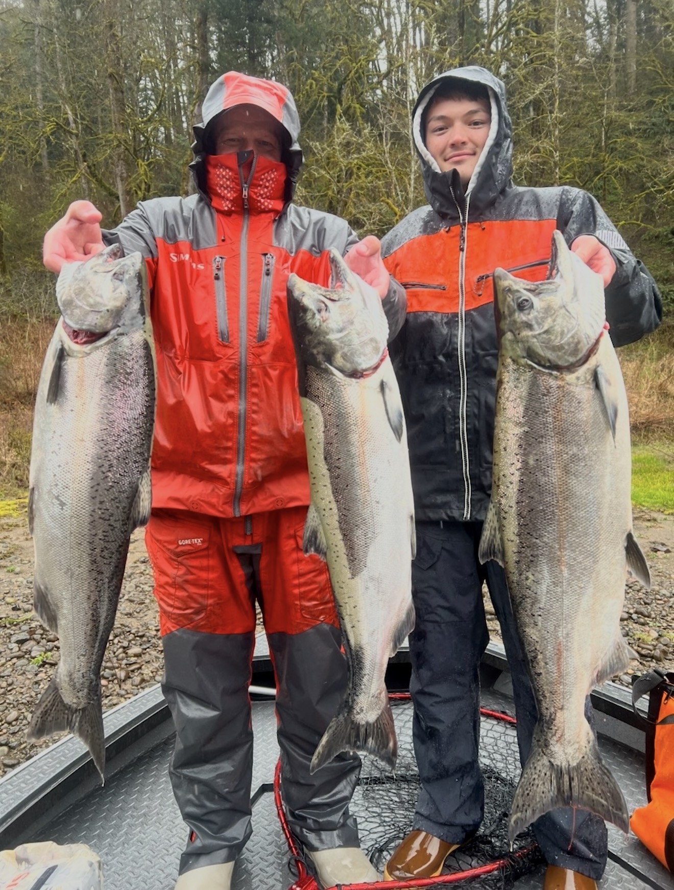 Two anglers in rain gear with three big Chinook salmon on the boat