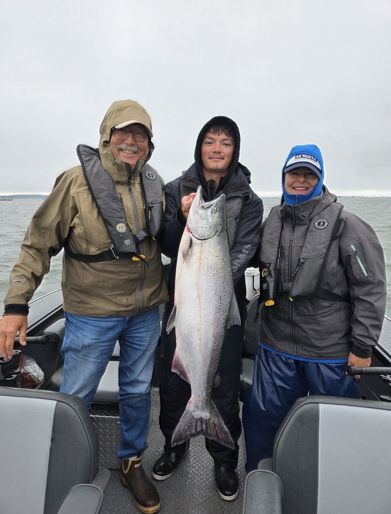 Family on the boat with a bright ocean Chinook salmon